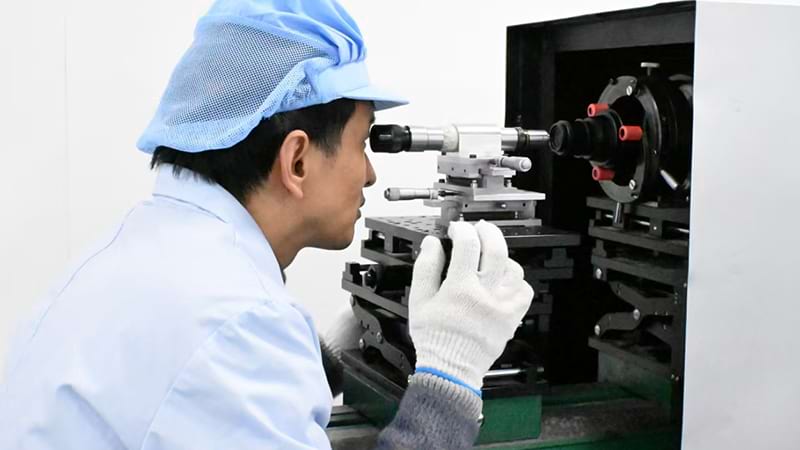 Optical lens assembly station for low-light night vision goggles